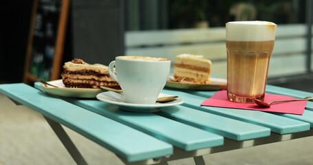 Cafe table features frothy latte and creamy cappuccino with gluten-free cakes. Delightful option for people following vegetarian or vegan diet