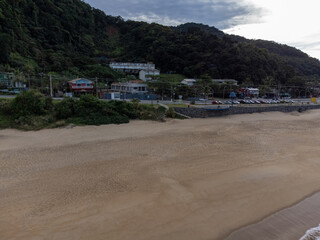 Fototapeta premium Beautiful coastal village on a beach with green waters and orange sand amidst the mountains