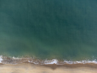bird's eye view of beautiful beach with orange sands and green water