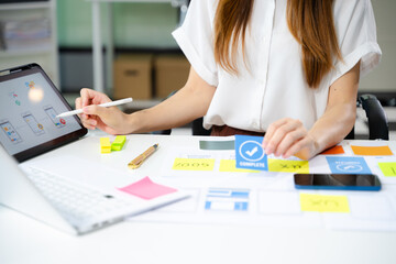 Creative UX UI designer working on app wireframe layout with sticky notes and color palette. web...