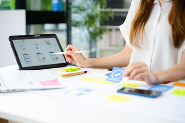 Creative UX UI designer working on app wireframe layout with sticky notes and color palette. web design, app development