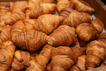 Freshly baked golden croissants stacked in a wooden tray. Crisp and flaky layers showcasing classic...