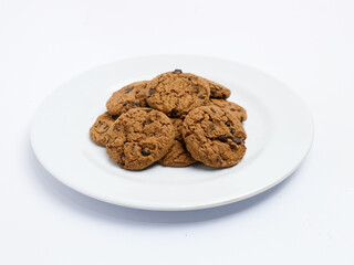 Chocolate chip cookies stacked on a white plate, isolated on a clean white background with a slight angle view.