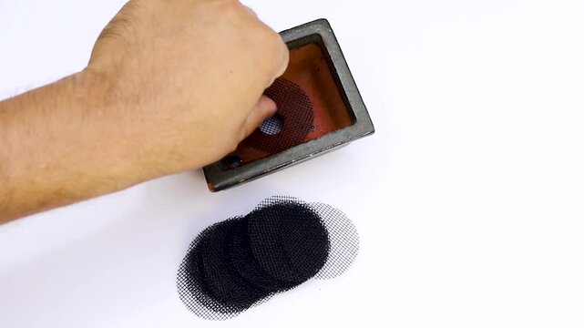 Hand placing mesh screen in bonsai pot for covering drainage hole on white background