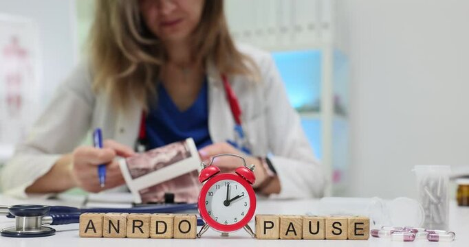 Word Andropause of wooden blocks with alarm clock and doctor with ultrasound scans. Woman medic checks male hormones level in medical office