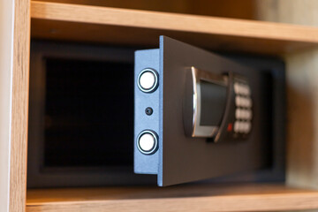 Fototapeta premium A secure safe with a digital keypad is partially open in a wooden cabinet. The safe has two circular buttons for operation and appears modern and functional