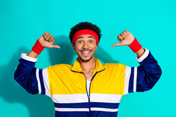 Retro styled young man in activewear smiling with backlit teal background emphasizing vibrant...