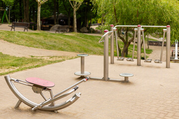 Various outdoor fitness machines are set up in a serene community park, providing a space for exercise and wellness