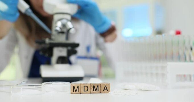 Scientist works with microscope and test tubes analyzing MDMA drug in modern laboratory. Pharmaceutical research in sterile laboratory environment
