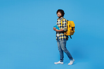 Full body side view young smart Indian boy student wear yellow casual clothes backpack bag hold...