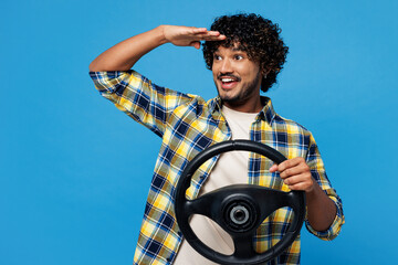 Young happy Indian man he wear yellow checkered shirt casual clothes hold steering wheel driving...