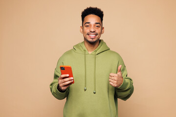 Young man of African American ethnicity wear green hoodie casual clothes hold in hand use mobile...