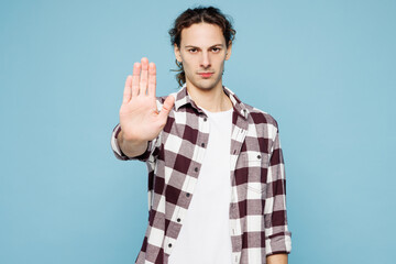 Naklejka premium Young sad strict man he wear purple checkered shirt casual clothes showing stop gesture with palm looking camera isolated on plain pastel light blue cyan background studio portrait. Lifestyle concept.