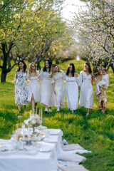 Women in elegant white dresses walk gracefully in a park