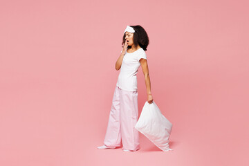 Full body calm young woman wear pyjamas jam sleep eye mask rest relax at home stand hold pillow...