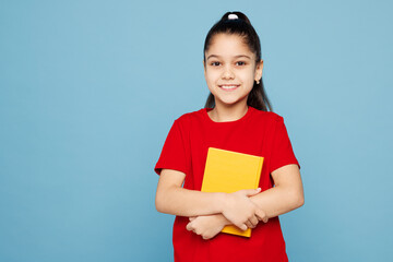 Obraz premium Little kid girl 8-9 years old wears red t-shirt have fun holding read book look camera isolated on pastel light blue color background child studio portrait. Mother's Day love family lifestyle concept.
