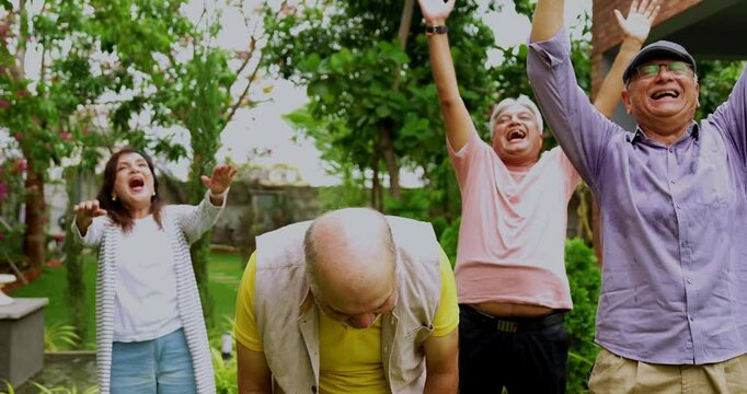 Seniors enjoying in laughter club outdoors, Indian Asian old age friends standing in lush green garden bursting in laughter with positive expressions in morning healthy activity