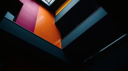 A low-angle view of a building's interior. Walls of purple, orange, and yellow appear to be stacked around a central open space.