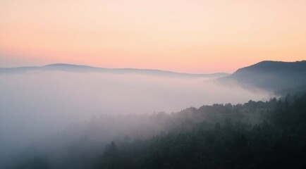 Fototapeta premium Mountains and forest landscape shrouded in mist at sunrise or sunset.