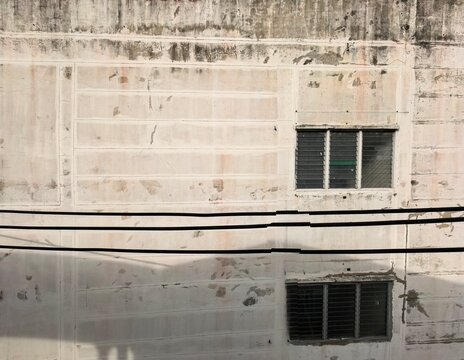 Aged and dirty concrete building wall with windows and wires. - Powered by Adobe