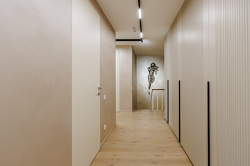 A long hallway has beautiful wooden floors and a painting