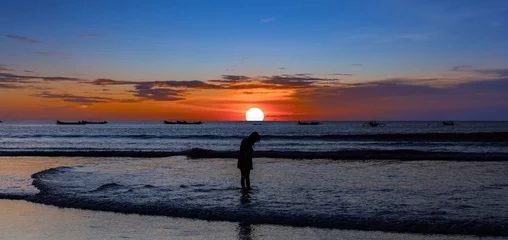Fototapeten Bali Beautiful colourful sunset on Kuta Beach on the island of Bali blue purple orange skies with turquoise blue waters and silhouette of people on the sandy beach the land of gods Bali Island Indonesia   © Elias Bitar