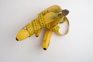 Yellow banana with measuring tape on light background.
Weight loss concept. Men's health concept.