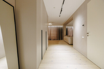 A long hallway with a wall mirror and a door to another room