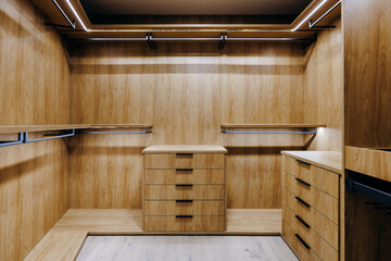 A spacious walkin closet featuring elegant wooden cabinets and drawers