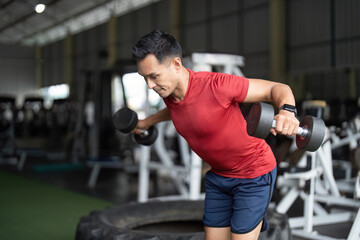 Wellness through Strength Training. Man executing bent-over dumbbell fly in gym.