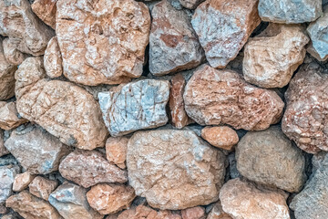 Close-up view of a stone wall in Alanya Castle, Turkey, showing a variety of textured rocks in different shades. The stones form a rustic, natural pattern, creating a historical atmosphere