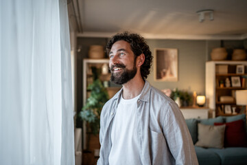 Happy man smiling and looking out the window at home