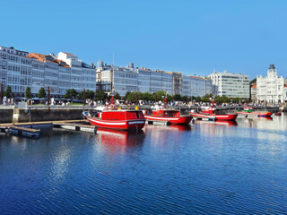 Coruna port with professional fishing boats , sailboats and yachts moored and typical buildings with elegant glass facade , Galicia , Spain