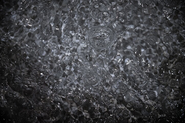 Black water with ripples. Defocus blurred black clear calm water surface texture with splashes and bubbles.