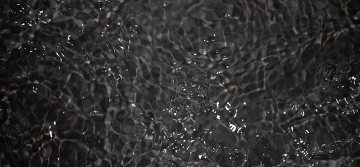 Black water with ripples. Defocus blurred black clear calm water surface texture with splashes and...