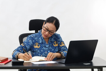 Serious expression young woman working at a desk writing notes in a notebook conceptual of a...