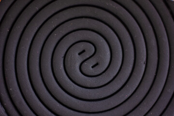 Obraz premium A close-up of a dark, spiraling object, possibly a mosquito coil, forming a continuous geometric pattern with a subtle yin-yang like center, creating an abstract and intriguing texture.