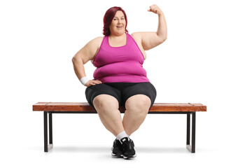 Obraz premium Plus size woman in sportswear sitting on a bench and showing arm muscles