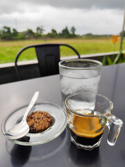 A cup of hot black coffee with other accompaniments, served in a natural themed cafe.