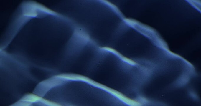 Pool ripples at night in dim lamp light dark background