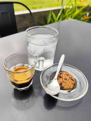 A cup of hot black coffee with other accompaniments, served in a natural themed cafe.