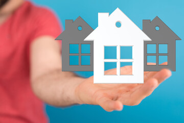 Image of a hand holding 3D house models, ideal for real estate, home buying, and property...