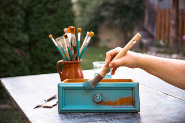 Painting a wooden furniture outdoors, an eco-friendly re-use business.