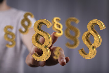 Plakat Hand reaching for 3D golden paragraph symbols. Legal concept.