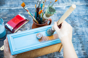 Painting a wooden furniture outdoors, an eco-friendly re-use business.