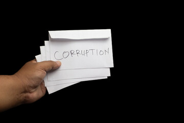 Adult men Hand holding CORRUPTION envelopes on black background. Bribery, fraud, unethical...