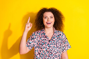 Excited young woman gesturing with enthusiasm on a vivid yellow background showing joy, energy, and...