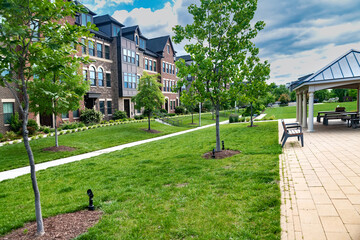 Modern apartment building with green walking area and gazebo. Urban development, landscaping.