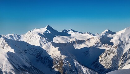 Naklejka premium majestic aerial view of snow capped mountain range under clear blue sky with soft light and shadows on the snowy slopes