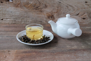 White Tea pot and cups of hot beverage on wooden.